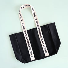 Load image into Gallery viewer, Black tote bag with motivational quote on pink straps against a light blue background
