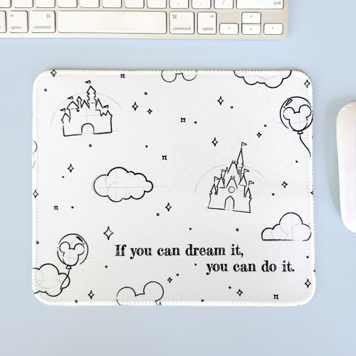 Mouse pad with castle and cloud design on a light blue surface with keyboard and mouse.