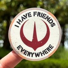 Load image into Gallery viewer, Circular sticker with text &#39;I have friends everywhere&#39; held by a hand against a blurred green background
