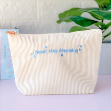 Load image into Gallery viewer, Corduroy pouch in cream color with blue embroidered quote &quot;Never Stop Dreaming&quot; surrounded by sparkle magic stars. 

