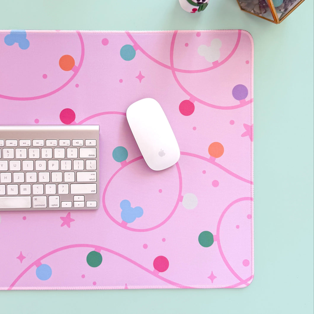 Pink mouse pad with colorful patterns on a light blue surface, featuring a keyboard and mouse.