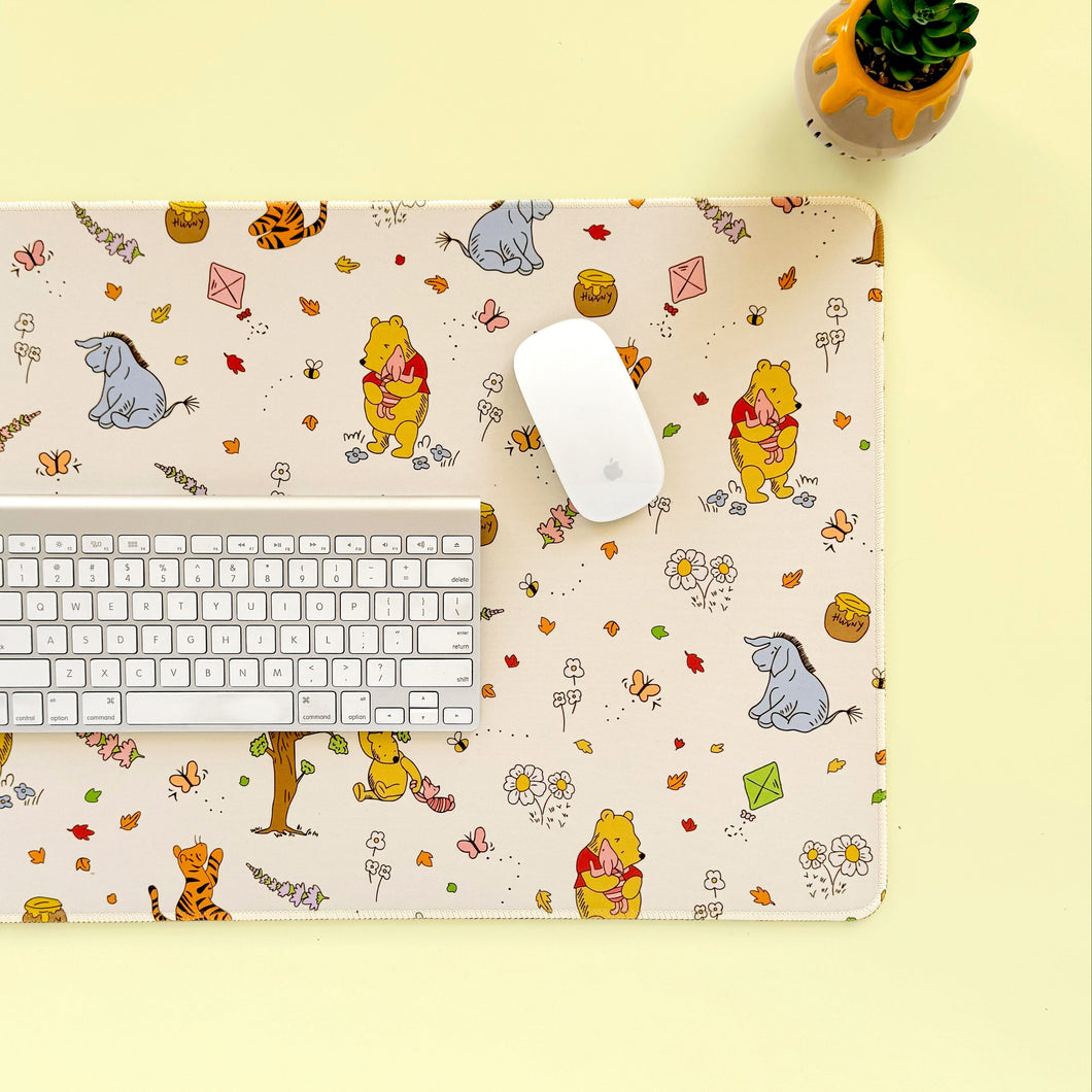 Desk setup with a Winnie the Pooh-themed desk mat, keyboard, and mouse on a yellow background.